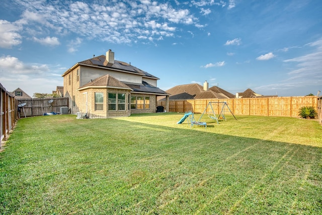 rear view of property featuring solar panels, a yard, and cooling unit