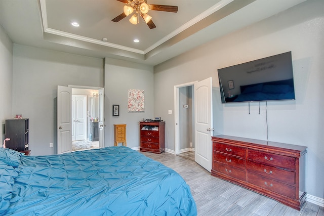 bedroom with a tray ceiling, light hardwood / wood-style flooring, ceiling fan, and crown molding