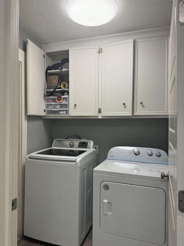 laundry area featuring washer and dryer, cabinets, and a textured ceiling