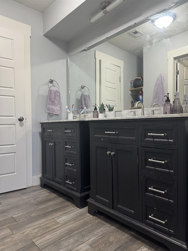 bathroom with vanity, a textured ceiling, and hardwood / wood-style flooring