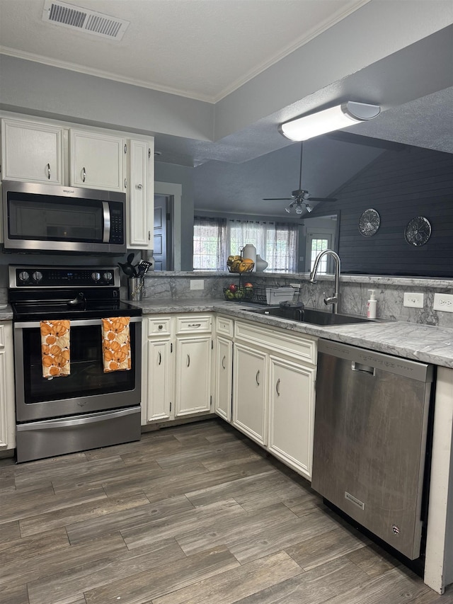 kitchen featuring sink, dark hardwood / wood-style floors, vaulted ceiling, white cabinets, and appliances with stainless steel finishes