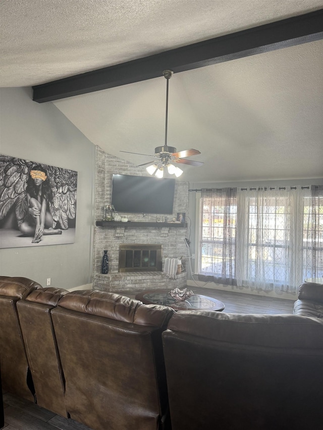 living room with a textured ceiling, ceiling fan, lofted ceiling with beams, a fireplace, and hardwood / wood-style floors