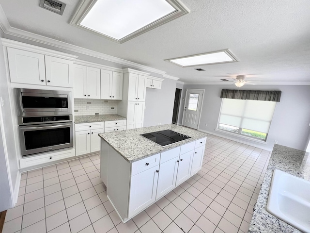 kitchen featuring light tile patterned floors, visible vents, ornamental molding, a center island, and stainless steel appliances