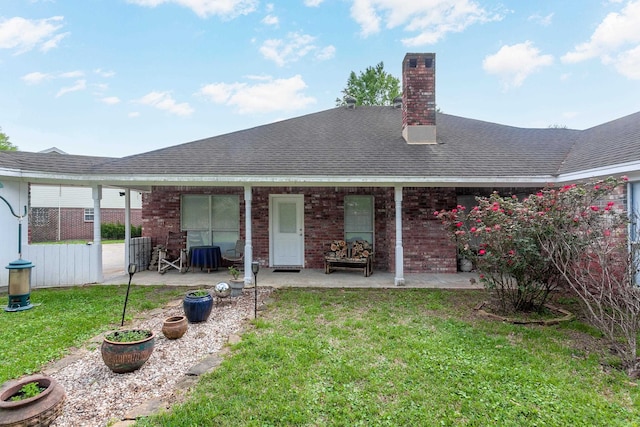 back of house featuring a shingled roof and a lawn