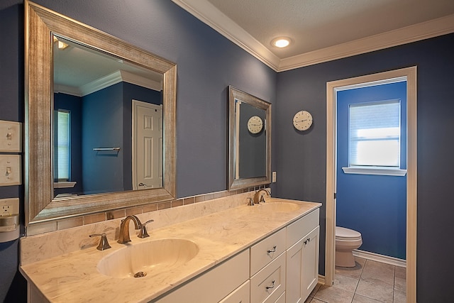 full bath featuring double vanity, ornamental molding, a sink, and toilet