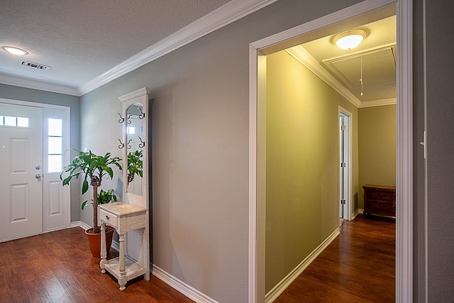 entryway featuring a textured ceiling, wood finished floors, visible vents, baseboards, and ornamental molding