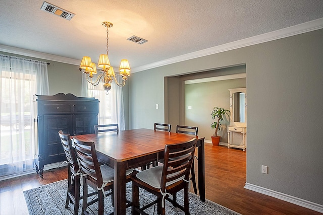 dining area featuring dark wood-type flooring, visible vents, crown molding, and a textured ceiling