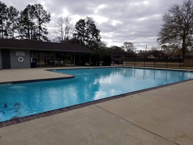 pool with a patio area and fence