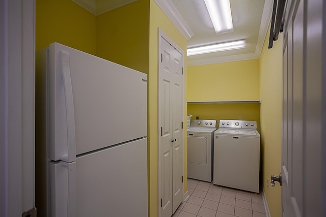 washroom featuring washing machine and dryer, laundry area, light tile patterned flooring, and crown molding