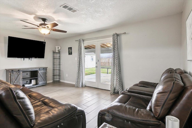 living room featuring french doors, ceiling fan, and a textured ceiling