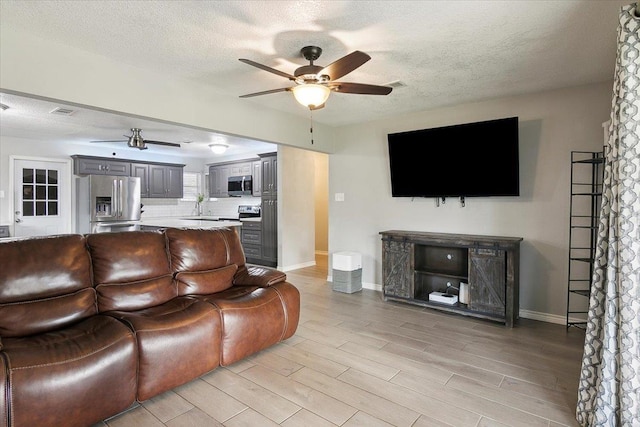 living room featuring sink, a textured ceiling, ceiling fan, and light hardwood / wood-style floors