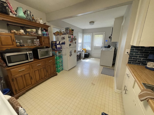 kitchen featuring washing machine and clothes dryer and white fridge