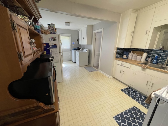 kitchen featuring white cabinetry, sink, tasteful backsplash, independent washer and dryer, and stove