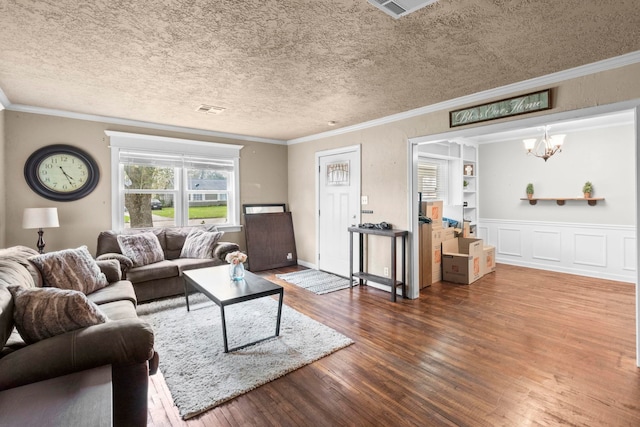 living area featuring visible vents, a textured ceiling, crown molding, and wood finished floors