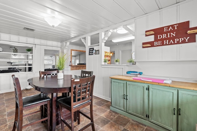 dining room featuring visible vents, wood ceiling, and stone finish floor