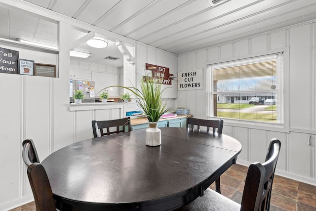 dining room with a decorative wall, visible vents, and stone finish flooring