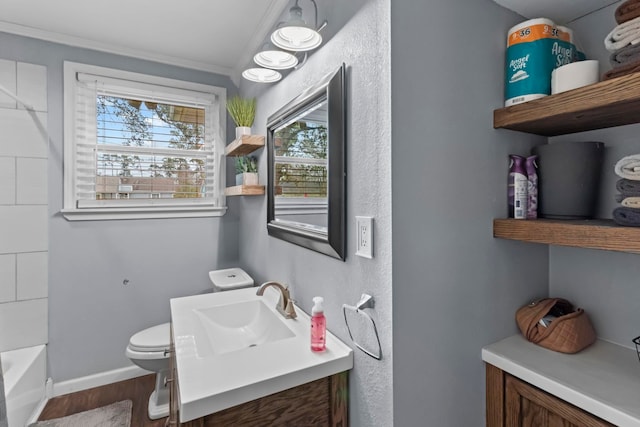 bathroom with toilet, wood finished floors, crown molding, baseboards, and vanity