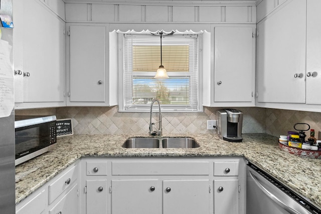 kitchen with a sink, stainless steel appliances, decorative backsplash, and white cabinetry