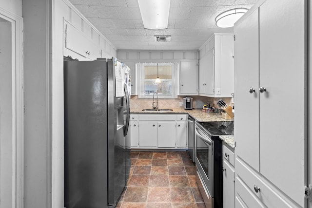 kitchen featuring stone finish floor, a sink, backsplash, appliances with stainless steel finishes, and white cabinets