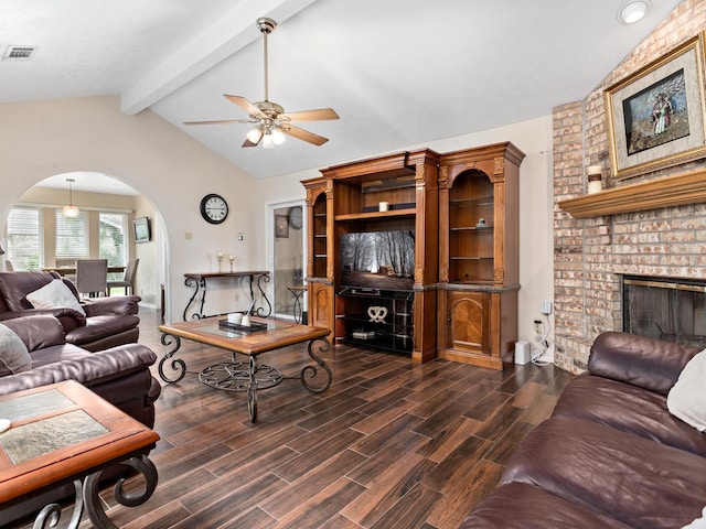 living room with vaulted ceiling with beams, ceiling fan, and a brick fireplace