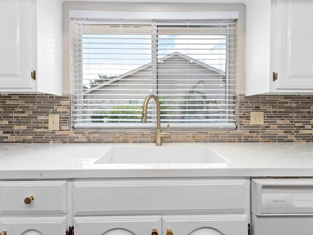 interior details with white cabinets, dishwasher, backsplash, and sink