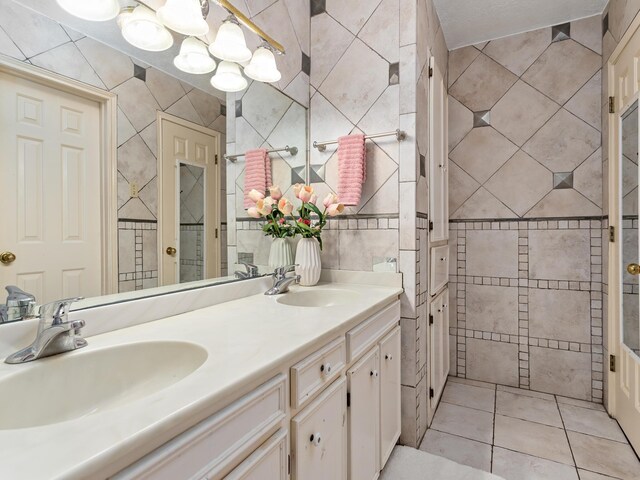 bathroom with tile patterned flooring, a textured ceiling, vanity, and tile walls