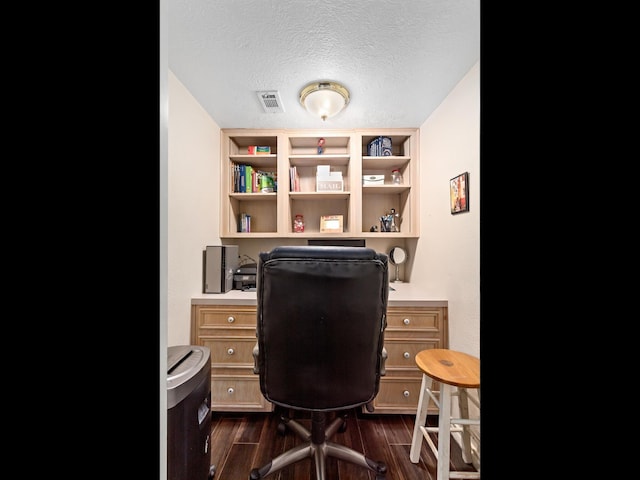 home office featuring built in shelves, dark wood-type flooring, and a textured ceiling