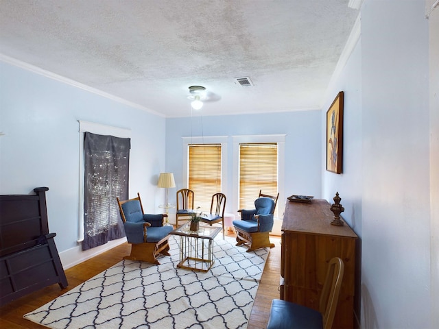 sitting room featuring hardwood / wood-style floors, a textured ceiling, and ornamental molding