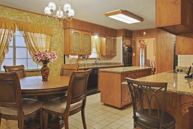 4425 Cartwright St, Beaumont, TX 77707 - kitchen with a textured ceiling, a kitchen island, black appliances, a chandelier, and light tile patterned floors