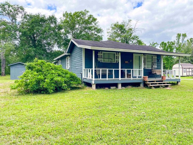 8140 Tx State Highway 62, Buna, TX 77612 - view of front of house with a porch, an outdoor structure, a front lawn, and a storage unit