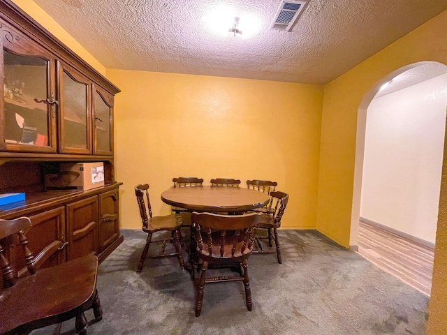 8140 Tx State Highway 62, Buna, TX 77612 - dining space with visible vents, dark colored carpet, arched walkways, and a textured ceiling