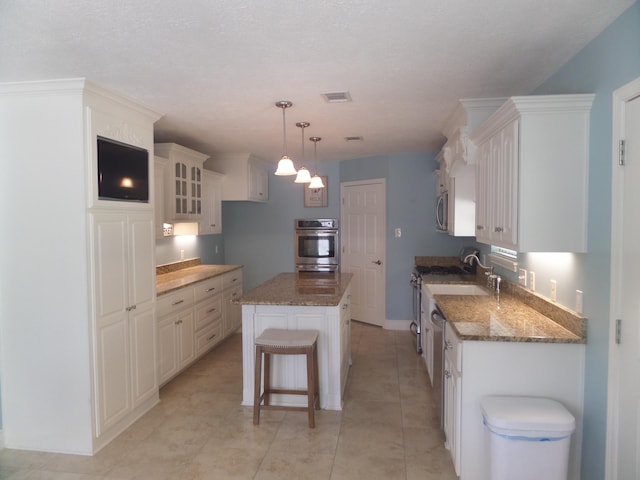 7035 Carroll Ln, Beaumont, TX 77713 - kitchen with appliances with stainless steel finishes, a center island, glass insert cabinets, dark stone countertops, and white cabinetry
