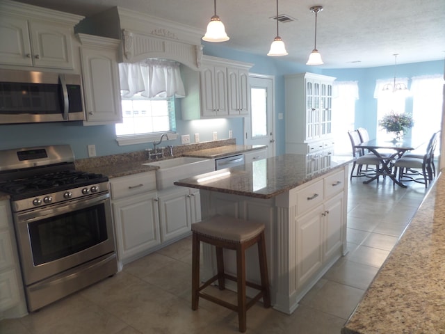 7035 Carroll Ln, Beaumont, TX 77713 - kitchen with stainless steel appliances, a kitchen island, a sink, light stone counters, and white cabinets