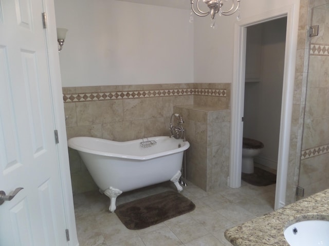 7035 Carroll Ln, Beaumont, TX 77713 - bathroom featuring tile walls, a freestanding tub, toilet, a sink, and a chandelier