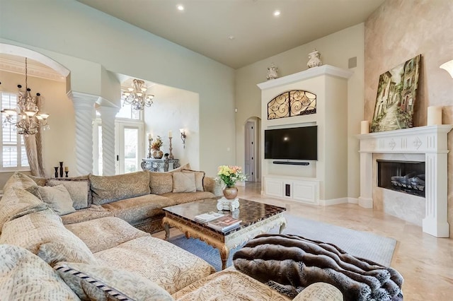 living room featuring an inviting chandelier, decorative columns, and a high ceiling