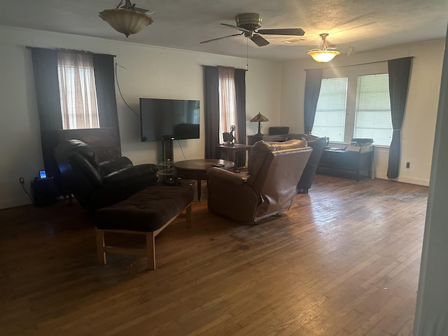 living area featuring ceiling fan and dark wood finished floors