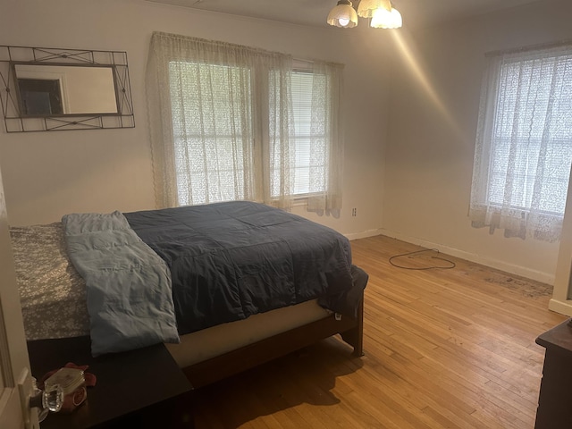 bedroom with a notable chandelier, baseboards, and wood finished floors