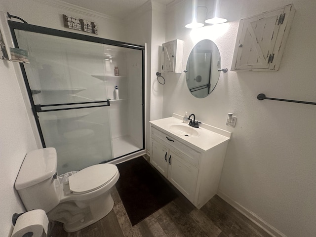 bathroom with toilet, wood finished floors, crown molding, vanity, and a shower stall