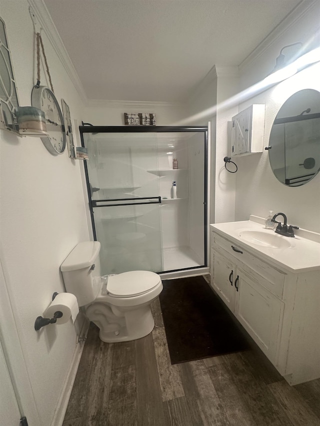 full bathroom featuring toilet, wood finished floors, vanity, ornamental molding, and a shower stall