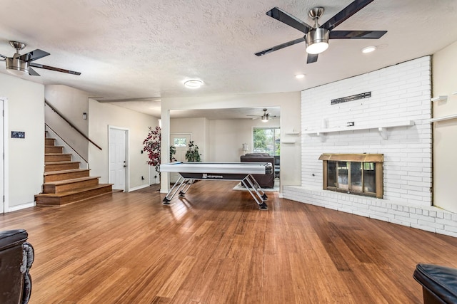 1385 Howell St, Beaumont, TX 77706 - playroom featuring a ceiling fan, a textured ceiling, wood finished floors, a fireplace, and recessed lighting