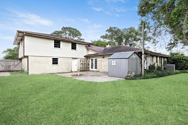 1385 Howell St, Beaumont, TX 77706 - back of house featuring french doors, a shed, a shingled roof, a lawn, and brick siding