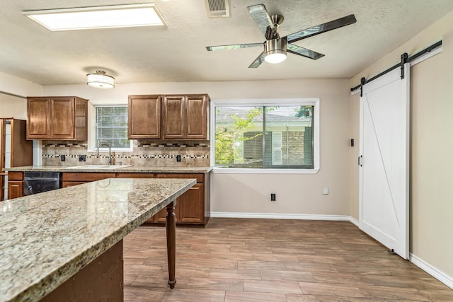 1385 Howell St, Beaumont, TX 77706 - kitchen with a ceiling fan, a barn door, wood finished floors, decorative backsplash, and a textured ceiling