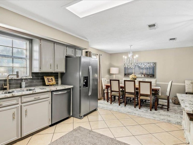 kitchen with gray cabinetry, stainless steel appliances, sink, pendant lighting, and light tile patterned flooring