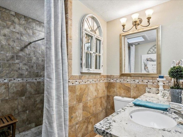 bathroom with vanity, a textured ceiling, tile walls, curtained shower, and a chandelier