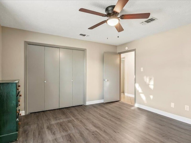 unfurnished bedroom featuring ceiling fan, a closet, hardwood / wood-style floors, and a textured ceiling