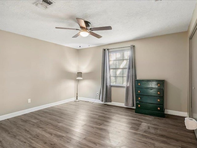 empty room with ceiling fan, dark wood-type flooring, and a textured ceiling