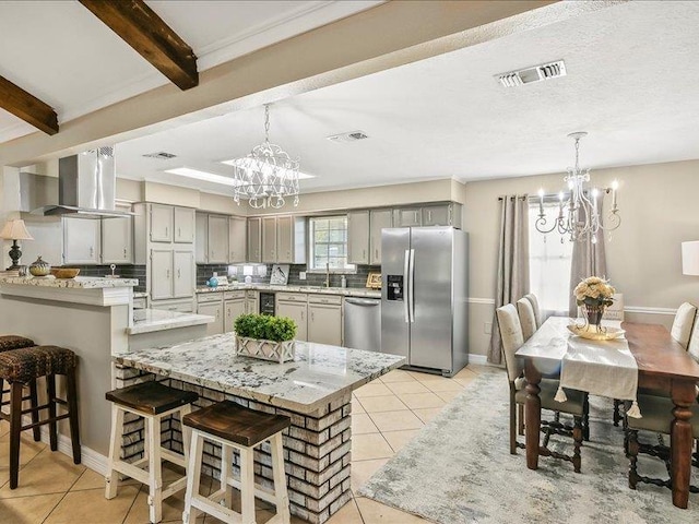 kitchen with beam ceiling, gray cabinetry, pendant lighting, and appliances with stainless steel finishes