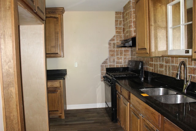 619 Carolyn St, Winnie, TX 77665 - kitchen with black gas range, under cabinet range hood, backsplash, brown cabinets, and dark wood finished floors
