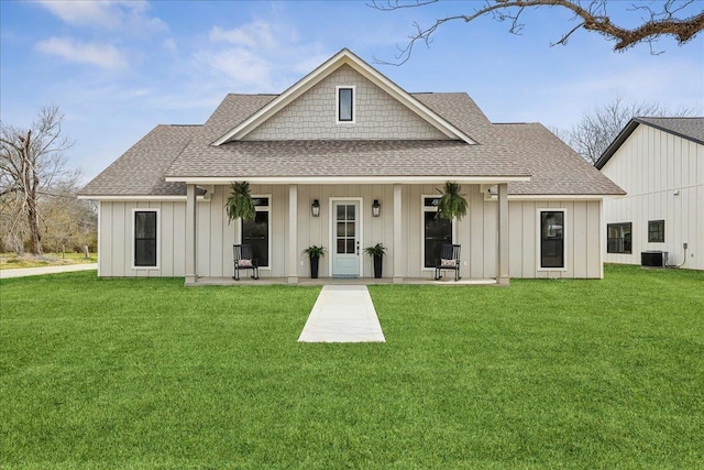 view of front facade with central air condition unit, board and batten siding, a front lawn, and roof with shingles