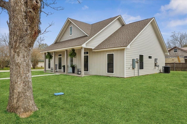 view of front of home featuring board and batten siding, roof with shingles, central AC, and a front lawn